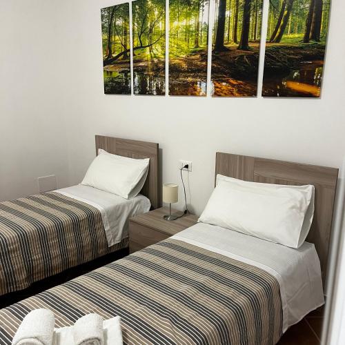 two beds in a room with paintings on the wall at Scapriccio Relax in Serrara Fontana