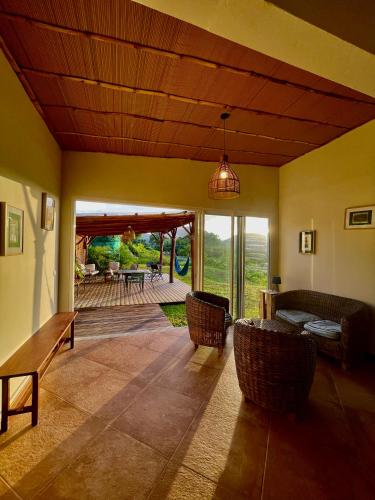 a living room with a couch and chairs and a porch at Chambre et SDB privative Roucou vue Mont Pelée dans maison partagée in Le Morne Rouge