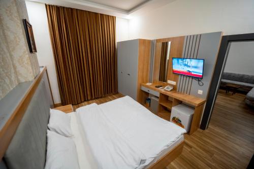 um pequeno quarto com uma cama e uma televisão em Havana Hotel em Dohuk
