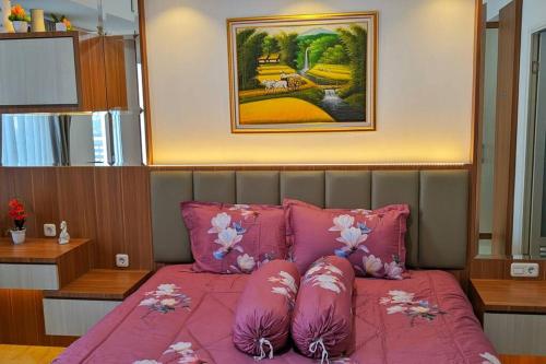a bedroom with a pink bed with pink pillows at The cozy & luxury room in Podomoro City Deli Medan in Medan
