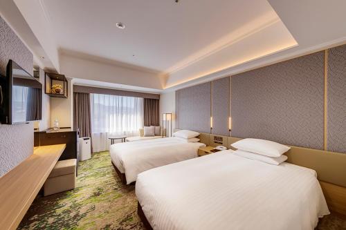 a hotel room with two beds and a television at Hotel Nikko Kumamoto in Kumamoto