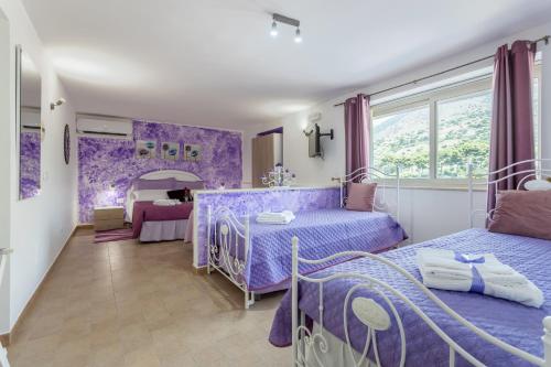 um quarto roxo com 2 camas e uma mesa em Villa Salvatore em Torretta