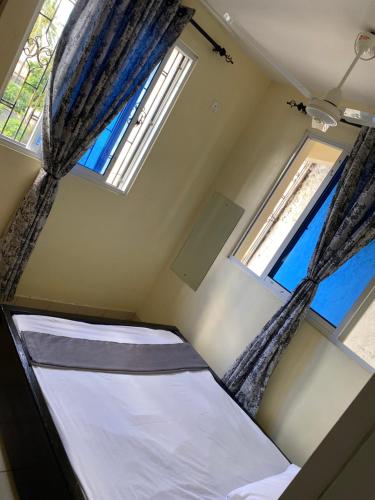 a small room with a bed and two windows at Kwetu House in Mombasa