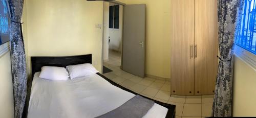 a small bedroom with a bed with white sheets and pillows at Kwetu House in Mombasa