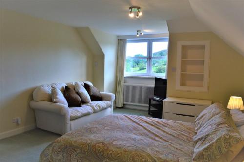 a bedroom with a bed and a couch and a window at Portling View in Dalbeattie