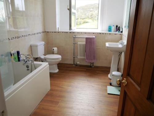 a bathroom with a tub and a toilet and a sink at Portling View in Dalbeattie