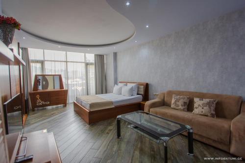 Hotel Nica في باتومي: غرفة معيشة مع أريكة وسرير وطاولة