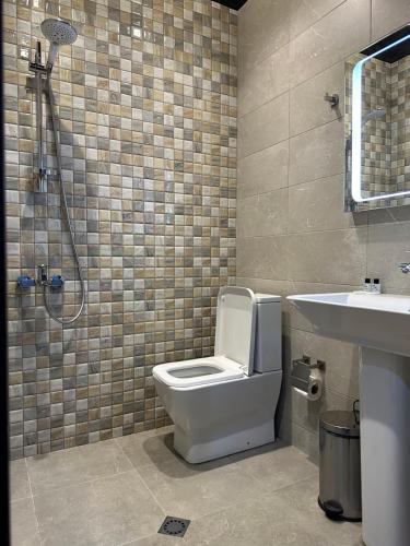 a bathroom with a toilet and a sink and a shower at Hotel Light Palace in Batumi