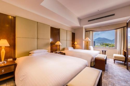 a hotel room with three beds and a window at Hotel Nikko Kumamoto in Kumamoto