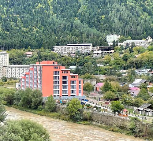 an orange building next to a river in a city at New apartments in borjomi in Borjomi