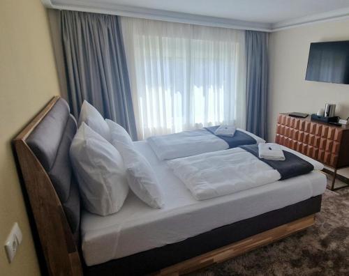 a bedroom with a bed with white pillows and a window at Hotel Rhin Inn in Fehrbellin