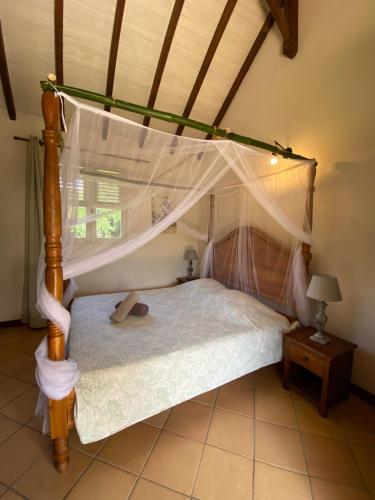 a bedroom with a bed with a canopy at Le relais de la montagne Pelée in Le Morne Rouge