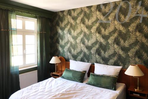 a bedroom with a bed with two green pillows at Rein Klassik Hotel in Bad Pyrmont