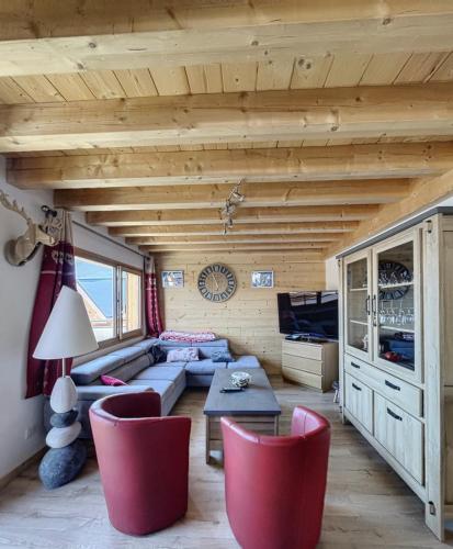 a living room with a couch and red chairs at Chalet la Cochette in La Toussuire