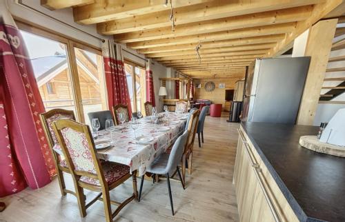 a long dining room with a long table with chairs at Chalet la Cochette in La Toussuire