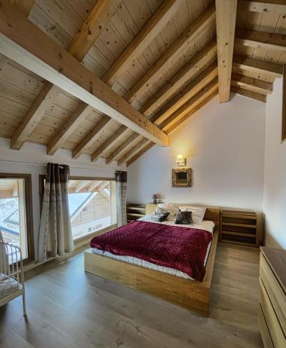 une chambre avec un grand lit dans une pièce avec des plafonds en bois dans l'établissement Chalet la Cochette, à La Toussuire
