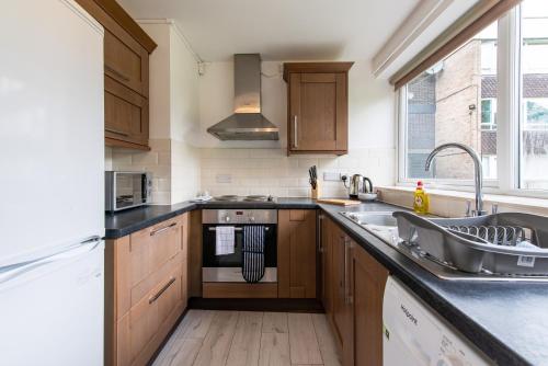 a kitchen with wooden cabinets and a sink at Stunning 2 Bedroom Apartments in Birmingham in Birmingham