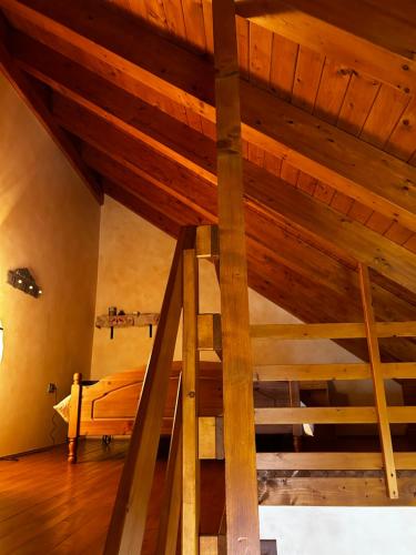 Cama elevada en habitación con techo de madera en Chalet Montana - Borgo Le stalle Lunghe, en Prato Nevoso