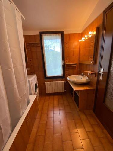 a bathroom with a sink and a tub and a window at La Casa del Nonno Franco in Colico