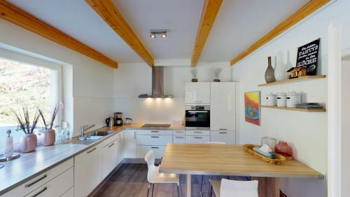 a kitchen with white cabinets and a wooden table at Villa Vicana in Kirchbach