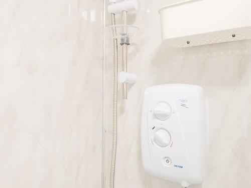 a shower in a bathroom with a white wall at Spacious Retreat near city centre Pass the Keys in Leeds