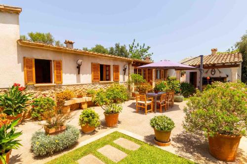 a garden with a table and chairs and a house at Can Vadell in Pollença