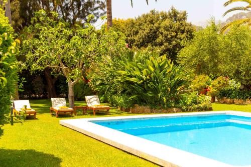 a swimming pool in a yard with chairs and trees at Can Vadell in Pollença