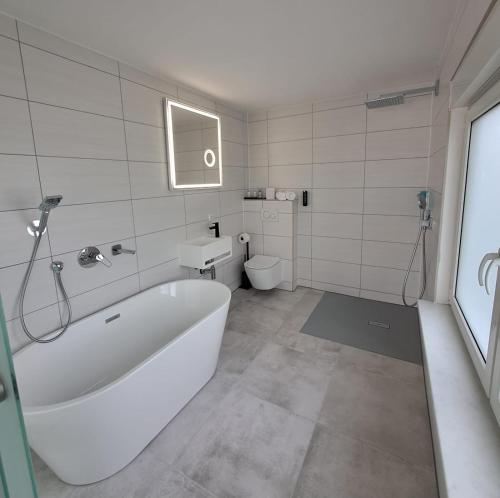 bagno bianco con vasca e servizi igienici di Hotel Rhin Inn a Fehrbellin