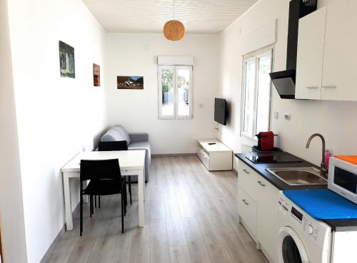 una pequeña cocina con mesa y comedor en Beau logement avec terrasse, jacuzzi et terrain de pétanque privatif à 5 minutes de la plage en Audenge