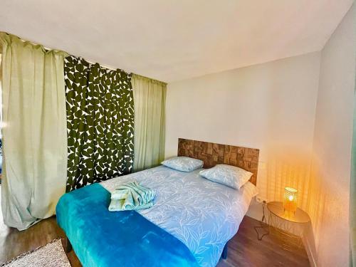 - une chambre avec un lit doté de draps bleus et une fenêtre dans l'établissement F2 rue d'Illiers, à Orléans