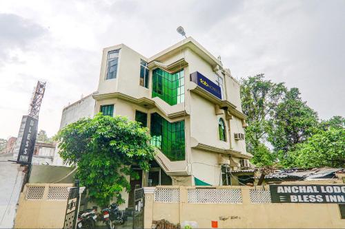 a tall white building with green windows at FabHotel Bless Inn in Allahābād