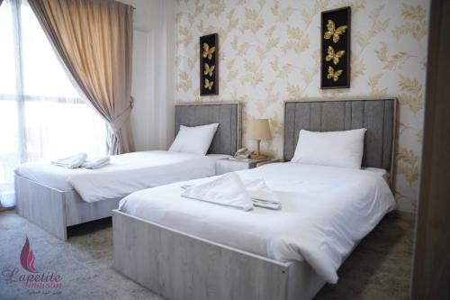 two beds in a hotel room with white sheets at فندق البيت الصغير - Lapetite Maison Hotel in Baghdād