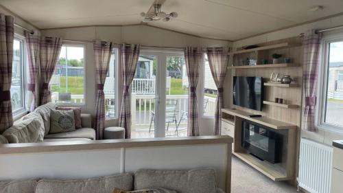 a living room with a couch and a tv at 3 Bedroom Caravan in Tattershall lakes Holiday Park in Tattershall