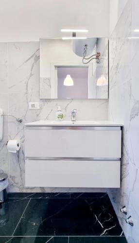 a white bathroom with a sink and a mirror at Guest Holiday Piave 4 in Reggio Emilia