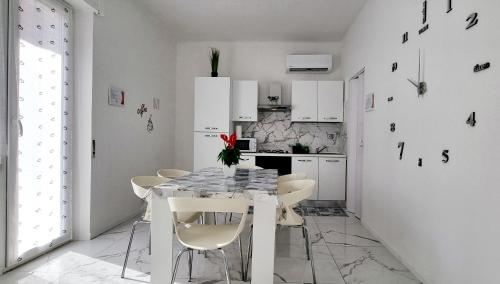 a white kitchen with a table and white chairs at Guest Holiday Piave 4 in Reggio Emilia