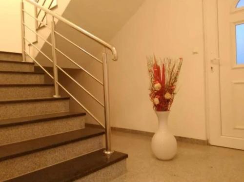 a white vase with flowers in it next to stairs at Villa Aurora in Međugorje