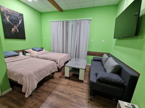 2 camas y un sofá en una habitación con paredes verdes en Stern Zimmer vermiten, en Hückelhoven