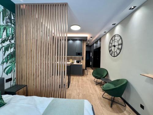 a bedroom with a bed and two green chairs at Apartament SPOT Klonowa in Kielce