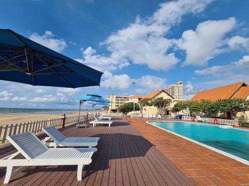 Hai Duong Intourco Resort, Vung Tau في فنغ تاو: مسبح وكراسي ومظلة بجانب الشاطئ