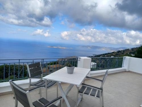 - une table et des chaises blanches sur un balcon donnant sur l'océan dans l'établissement Aegean Mirror, Andros, à Apróvaton