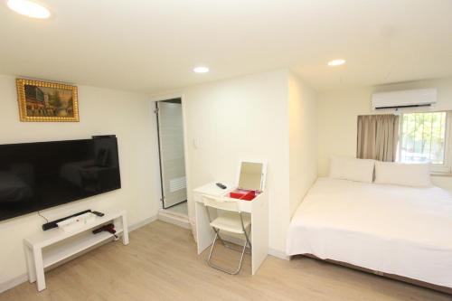 a bedroom with a bed and a desk and a tv at Sea Keelung in Keelung