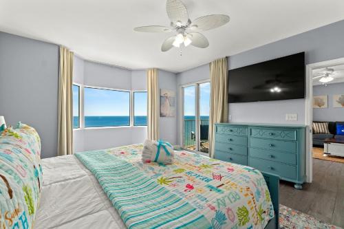 Schlafzimmer mit einem Bett mit blauer Kommode und Fenstern in der Unterkunft Tidewater Beach Resort 2505 - Sea Gem in Panama City Beach