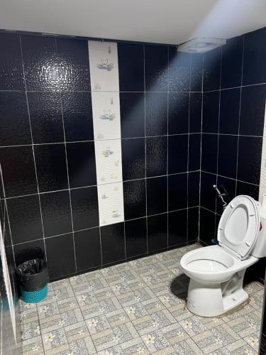 uma casa de banho com um WC e uma parede de azulejos pretos em ครูไสวโฮมสเตย์ 