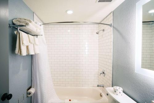 Super 8 by Wyndham Pueblo في بويبلو: حمام مع حوض أبيض ومغسلة