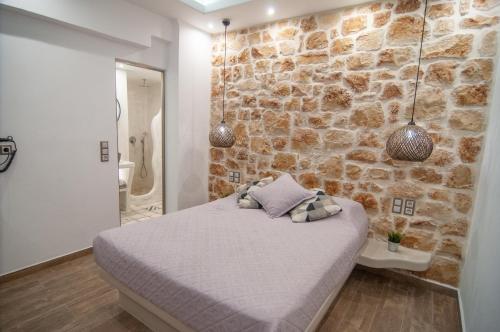 Un dormitorio con una pared de piedra y una cama en Katerina Roza Studios, en Naxos Chora