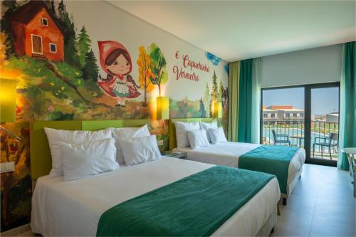 2 camas en una habitación de hotel con un mural de Navidad en Vila Gale Nep Kids, en Beja