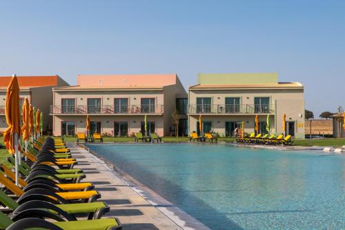 a swimming pool with yellow lounge chairs and buildings at Vila Gale Nep Kids in Beja