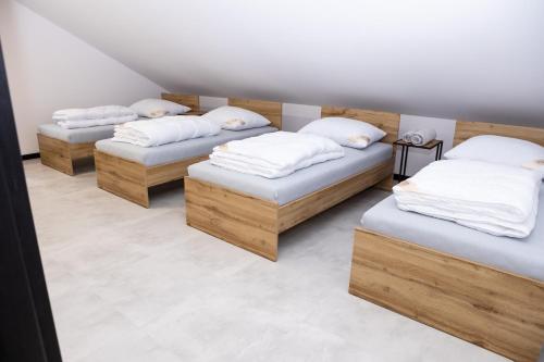 Cette chambre comprend 3 lits avec des oreillers blancs. dans l'établissement POKOJE JURAJSKI ZAKAMAREK, 