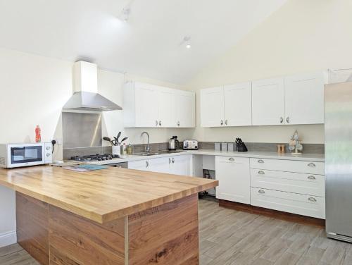 a kitchen with white cabinets and a wooden counter top at Millside, Bosham in Bosham