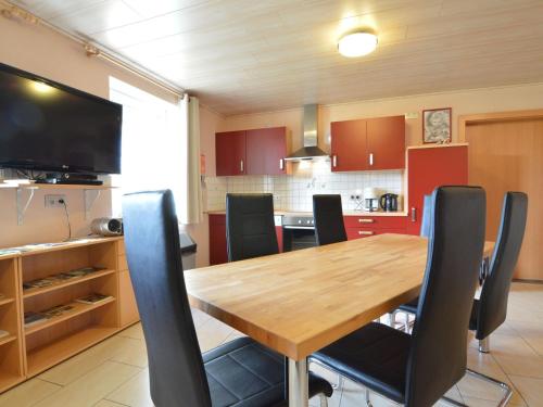 uma cozinha com uma mesa de madeira e cadeiras pretas em Comfy Holiday Home in Burg Reuland with Sauna Terrace BBQ em Burg-Reuland